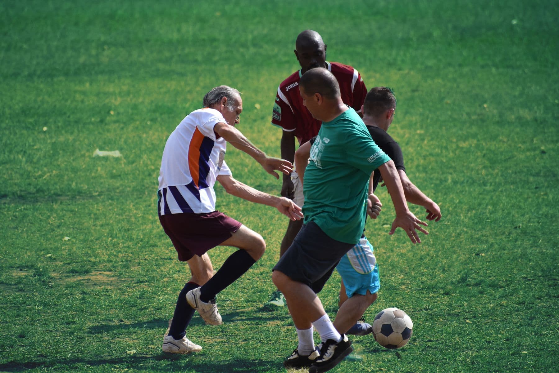 Adults playing soccer on a grass field